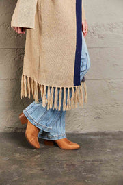 Khaki cardigan with fringe hem and navy trim, styled with flared jeans and boots.
