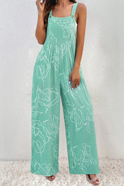 Turquoise botanical print wide-leg jumpsuit with adjustable straps and V-neck bodice.