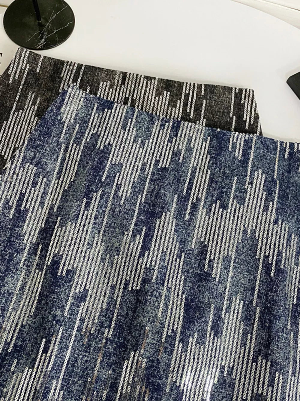 Shimmering sequin mini skirt in dark blue with vertical stripe pattern and zipper detail.