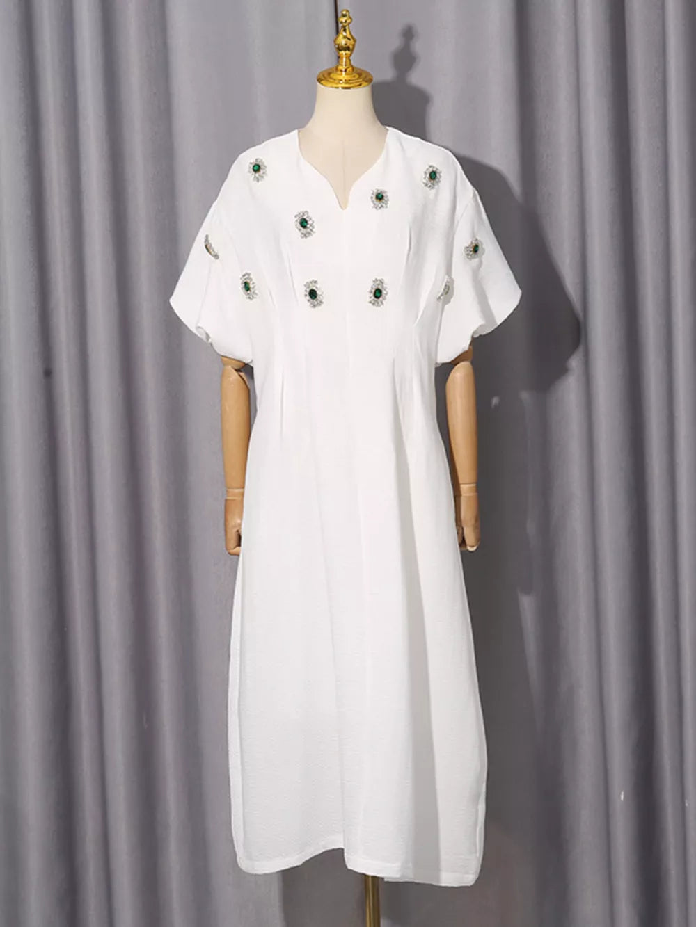 White midi dress with puff sleeves and scattered green rhinestone embellishments.