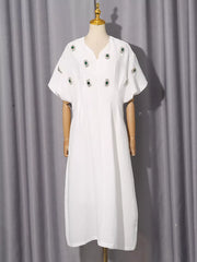 White midi dress with puff sleeves and scattered green rhinestone embellishments.