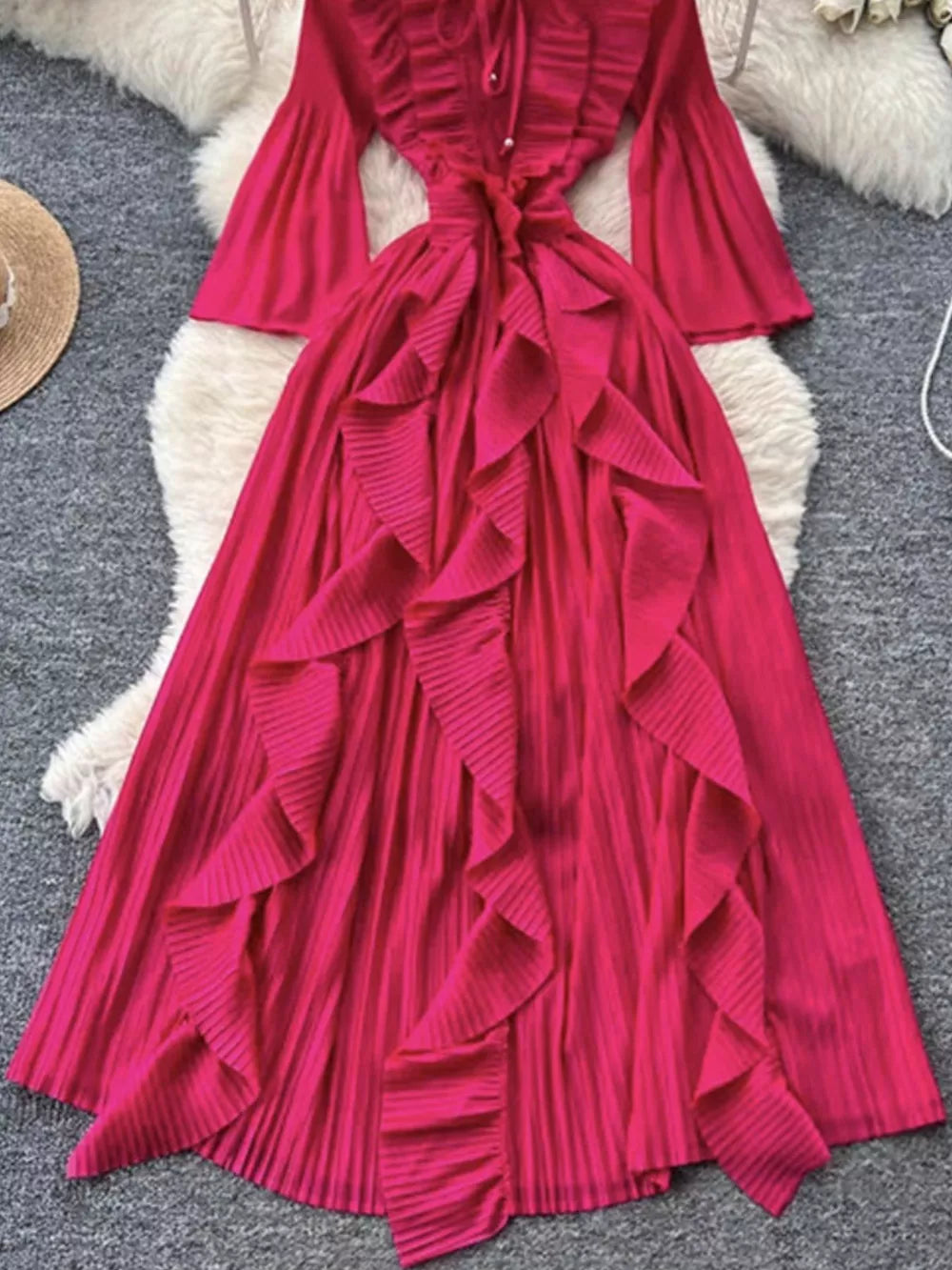 Pink A-line midi dress with cascading ruffles, bell sleeves, and tie neck.
