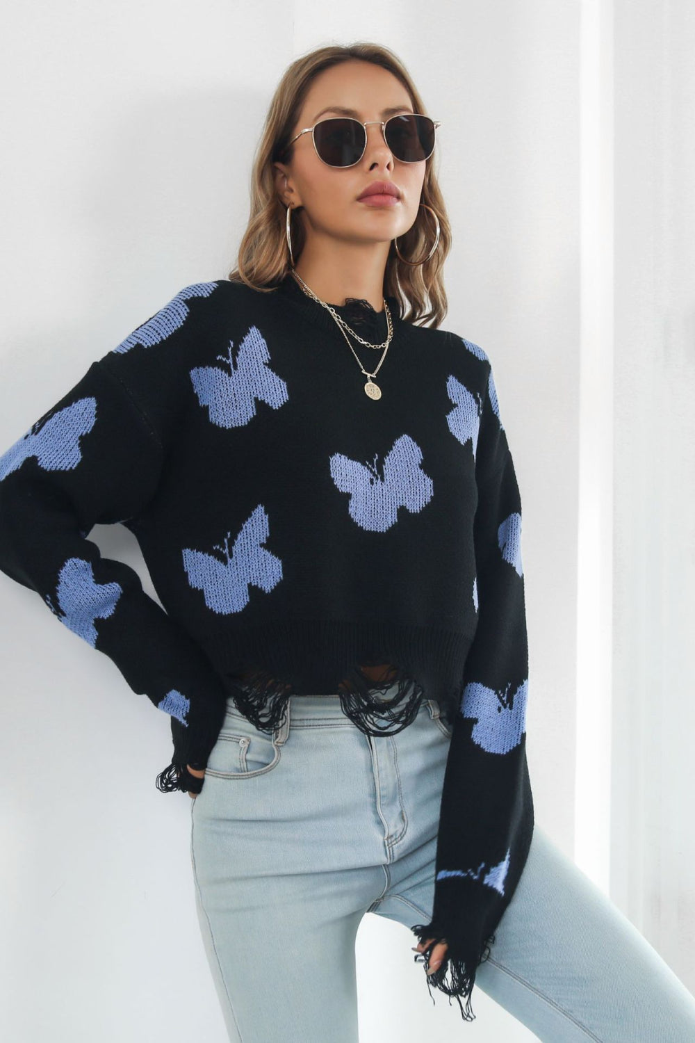 Black acrylic cropped knit sweater with butterfly intarsia and frayed hem.