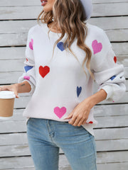 White knit sweater with bubble sleeves and a scattered heart motif in pink, red, and blue.