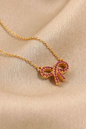 Gold bow pendant necklace with ruby embellishments