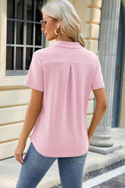 Textured blush pink polo shirt with V-neck detail and short sleeves.