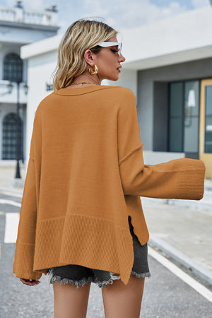 Caramel acrylic knit sweater with flared sleeves and slit hem detail.