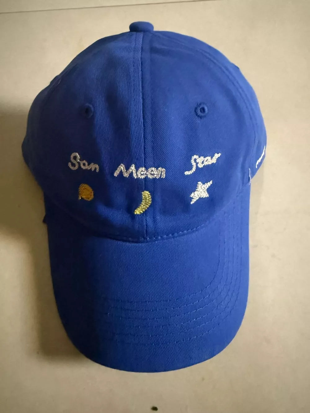 Royal blue cotton baseball cap with celestial embroidery of sun, moon, and stars.