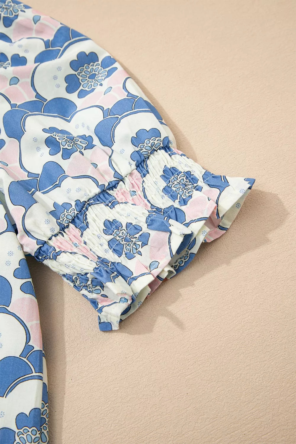 Blouse with blue and pink floral print, smocked cuffs, and frill detail.