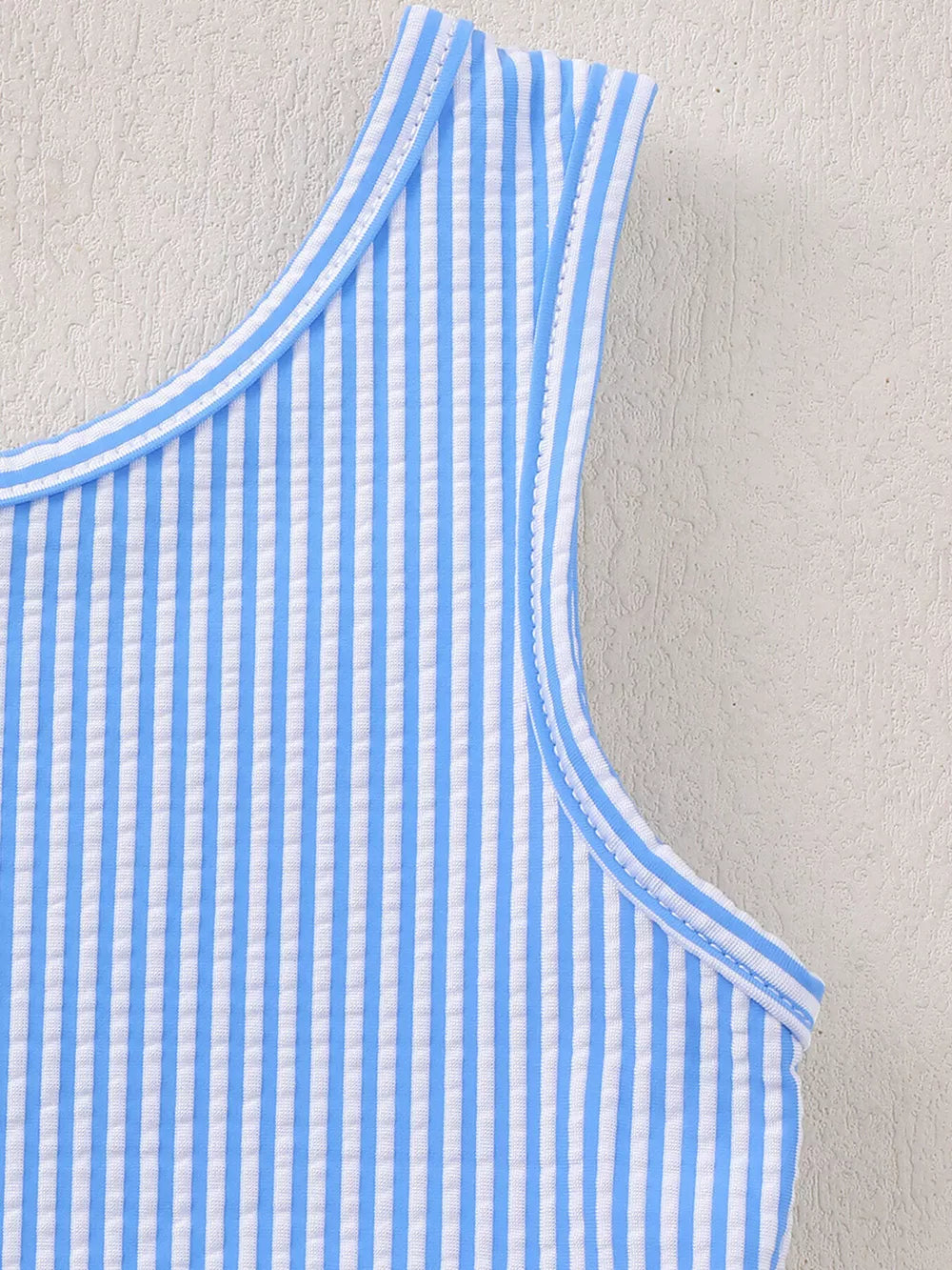 Blue striped seersucker one-piece swimsuit with ruffled trim detail.