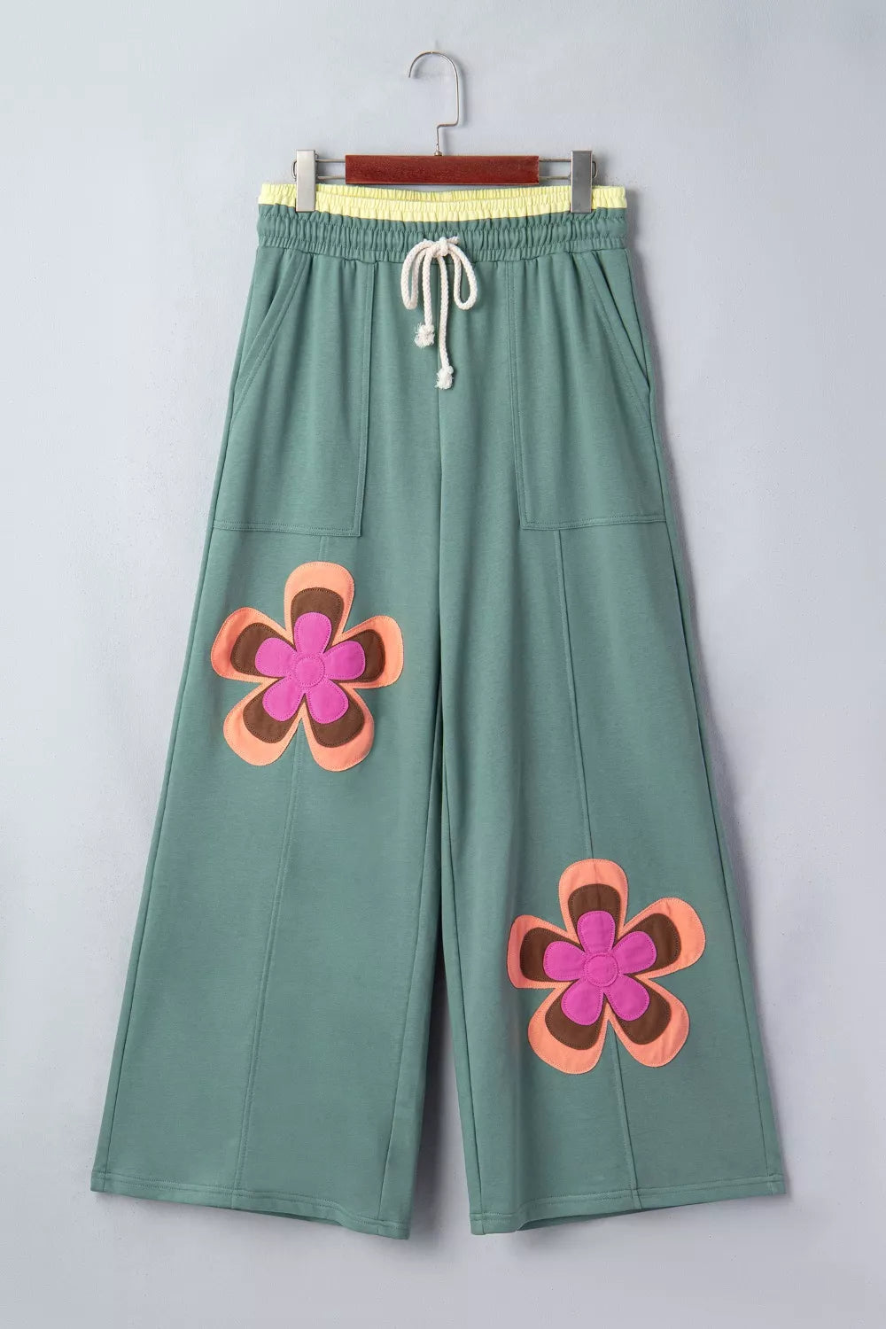 Green cotton sweatpants with wide legs, drawstring, and floral appliques.