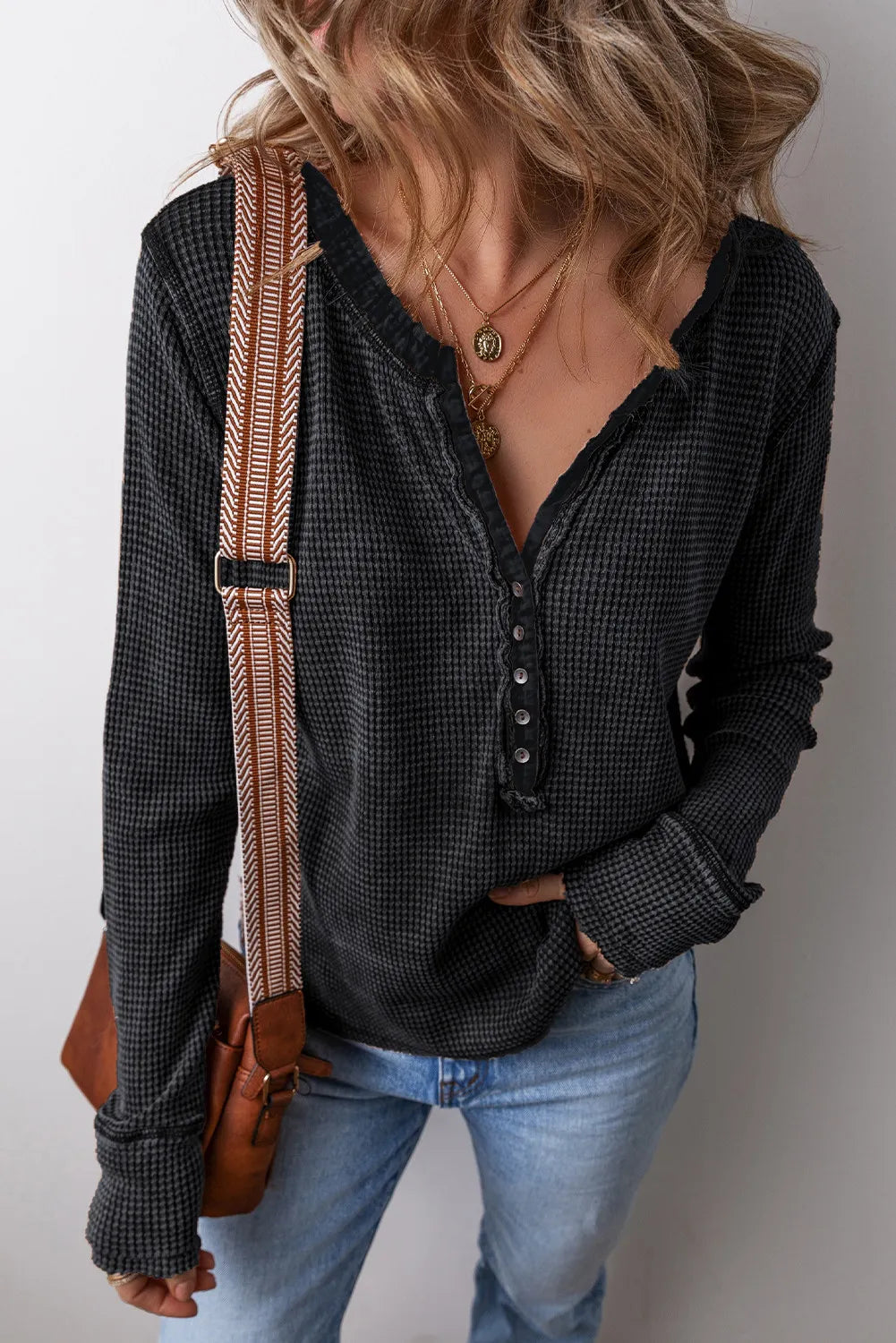 Black waffle knit henley blouse with button detail and raw edge neckline.