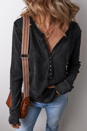 Black waffle knit henley blouse with button detail and raw edge neckline.