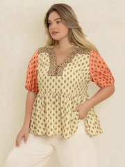 Vibrant geometric peplum shirt with coral sleeves and a v-neckline.