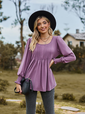 Dusty purple peplum blouse with gathered yoke and smocked cuffs, long sleeves.