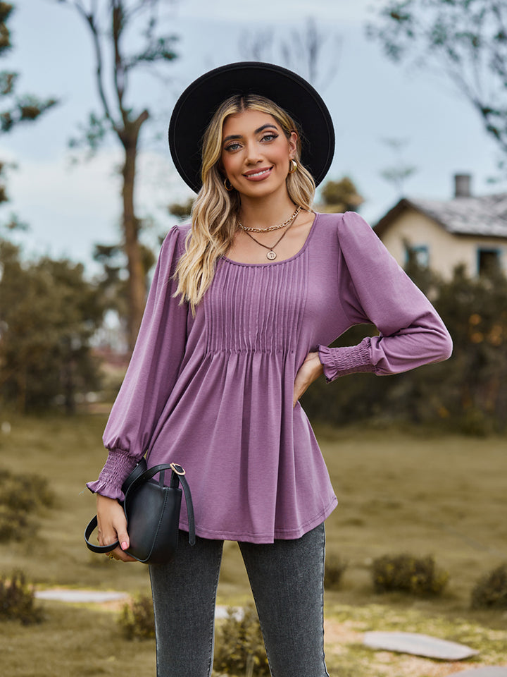 Dusty purple peplum blouse with gathered yoke and smocked cuffs, long sleeves.