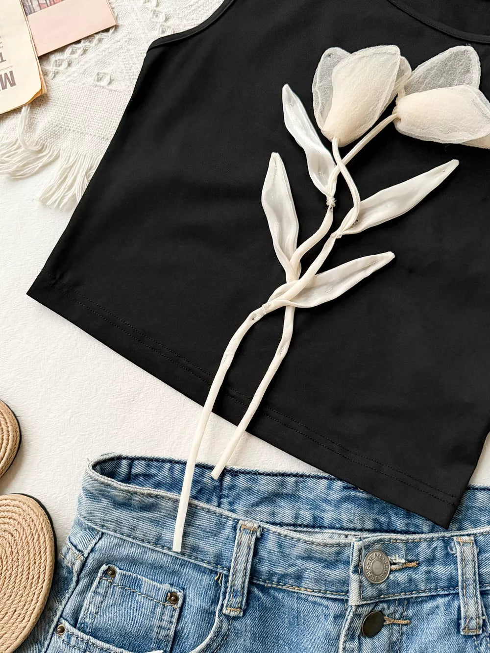 Black tank top with floral applique detail and round neck.