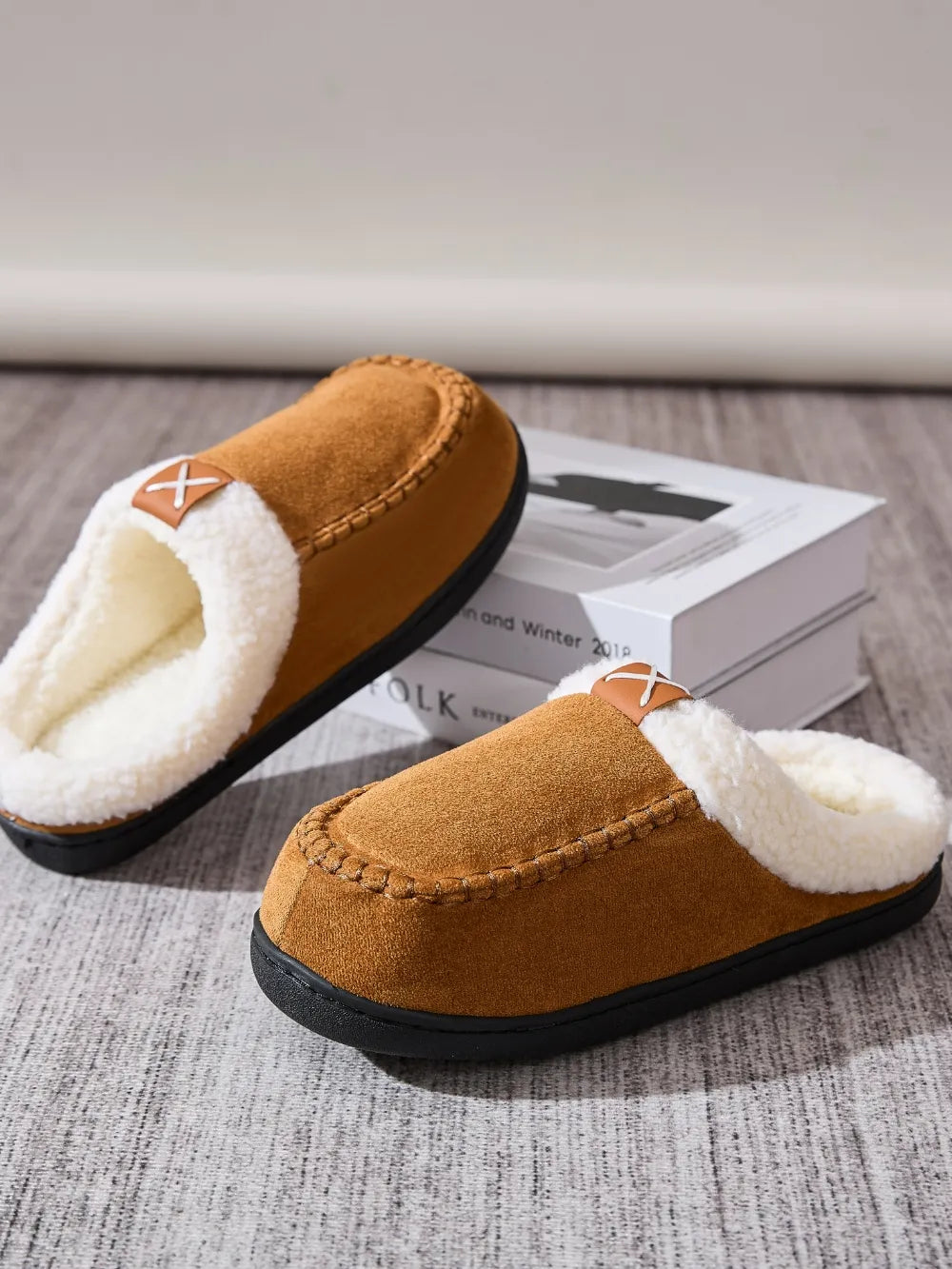 Caramel suede moccasin slides with white shearling lining and decorative stitching.