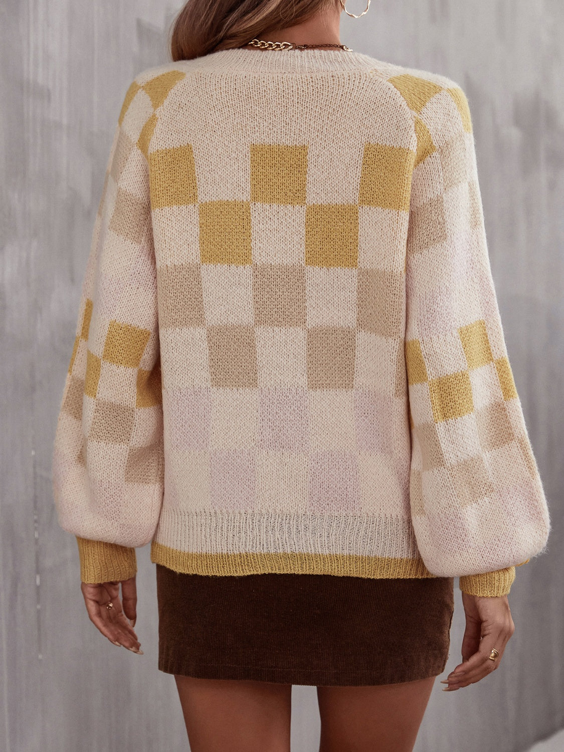 Geometric checkerboard knit sweater with puff sleeves in cream and light yellow.