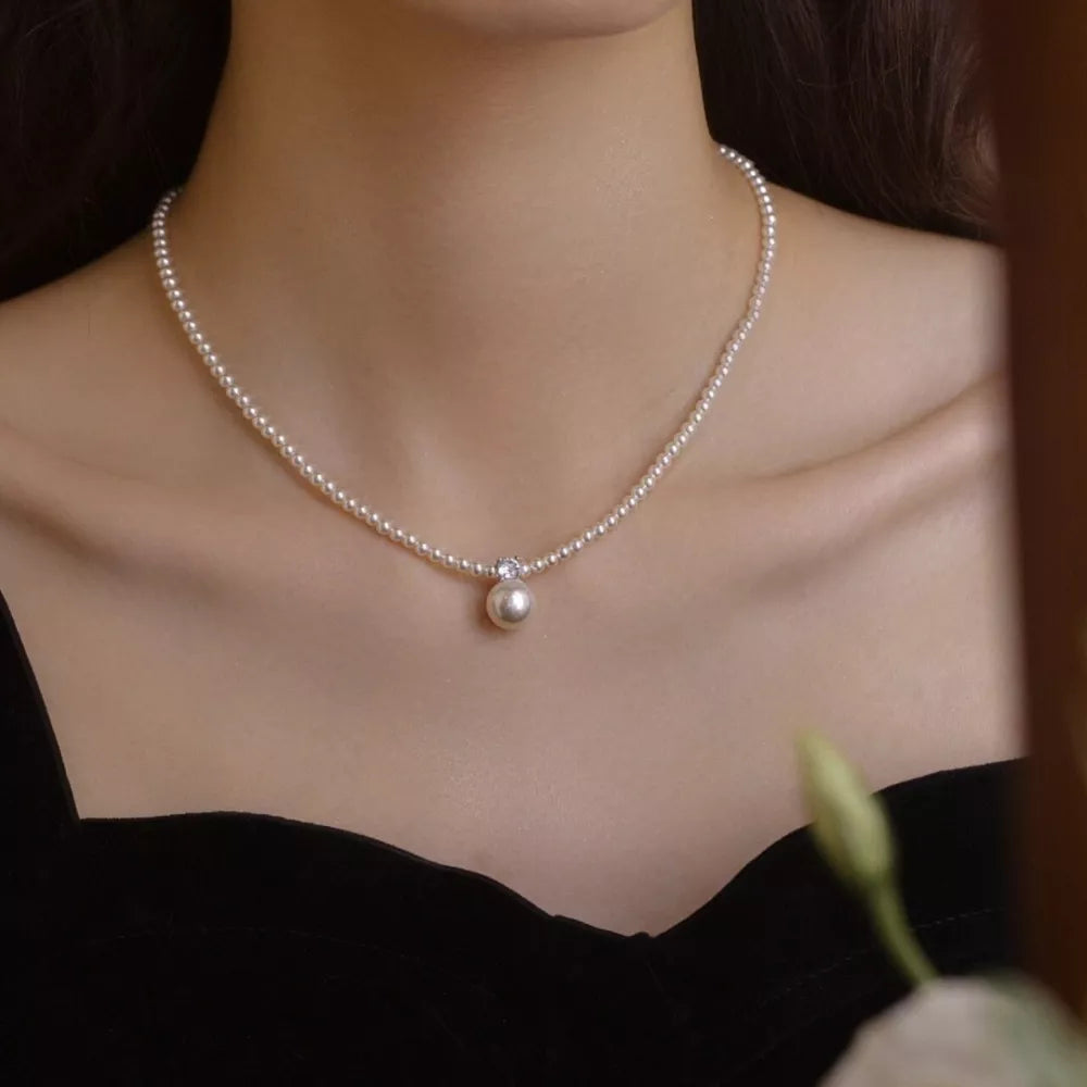Luminous pearl pendant choker necklace with a single pearl drop and crystal accent.