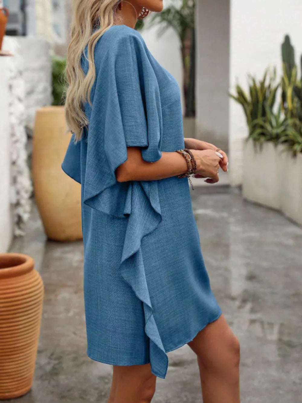 Blue V-neck mini dress with flowy sleeves and ruffled hem detail.