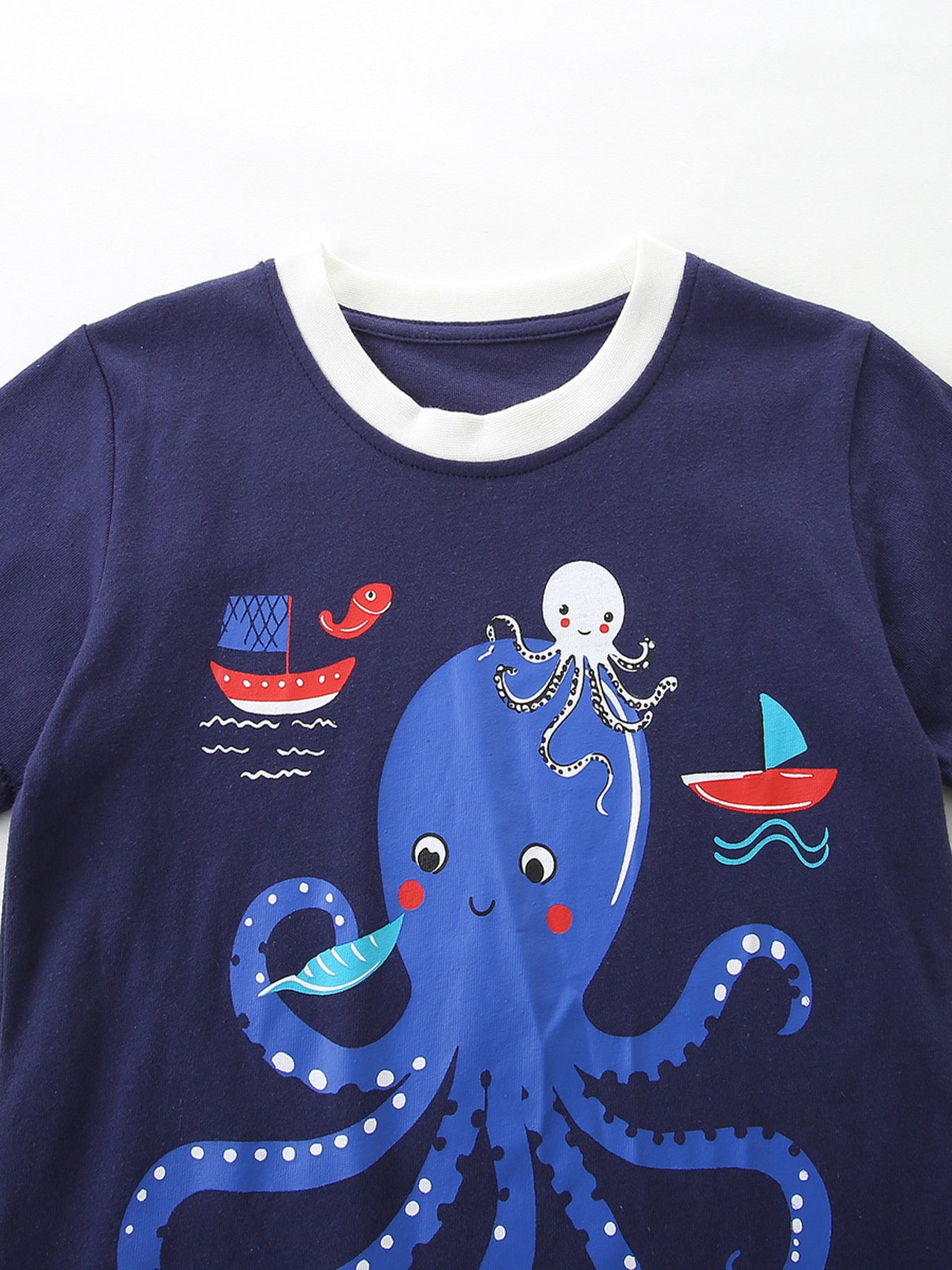 Navy cotton baby t-shirt with playful octopus and sailboat graphic, white trim neckline.