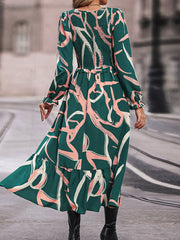 Midi dress in mid green with abstract print, smocked waist, long sleeves, and ruffled hem.