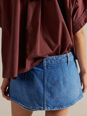 Classic denim mini skort in light blue with button closure and visible stitching.