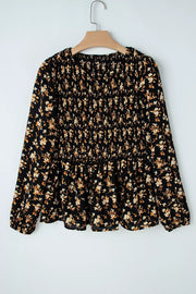 Black floral long-sleeve blouse with smocked waist and peplum hem.