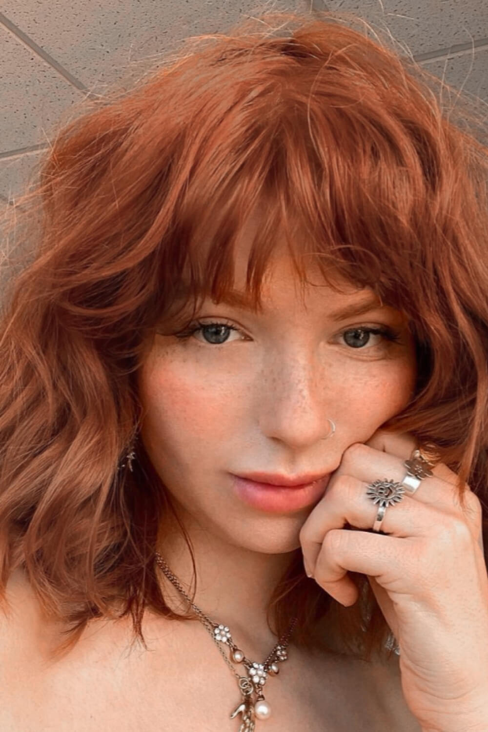 Rose Quartz bob wig with bangs in ochre, styled casually.