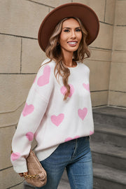 White acrylic knit sweater with pink intarsia hearts, crew neck, long sleeves.