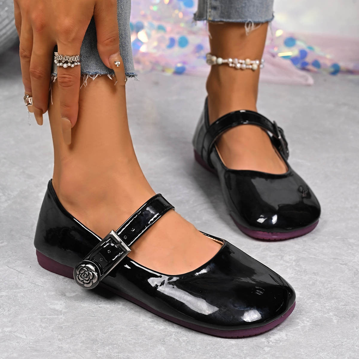 Black patent buckle strap Mary Jane loafers with rose detail.