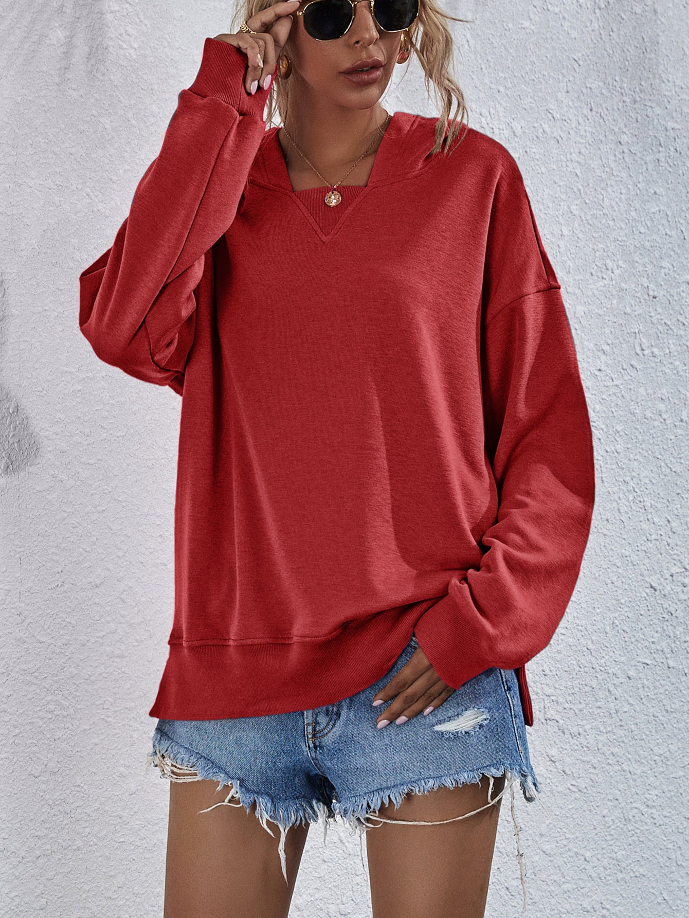 Boxy red hooded sweatshirt with split hem and wide neckline.