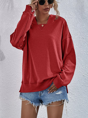 Boxy red hooded sweatshirt with split hem and wide neckline.