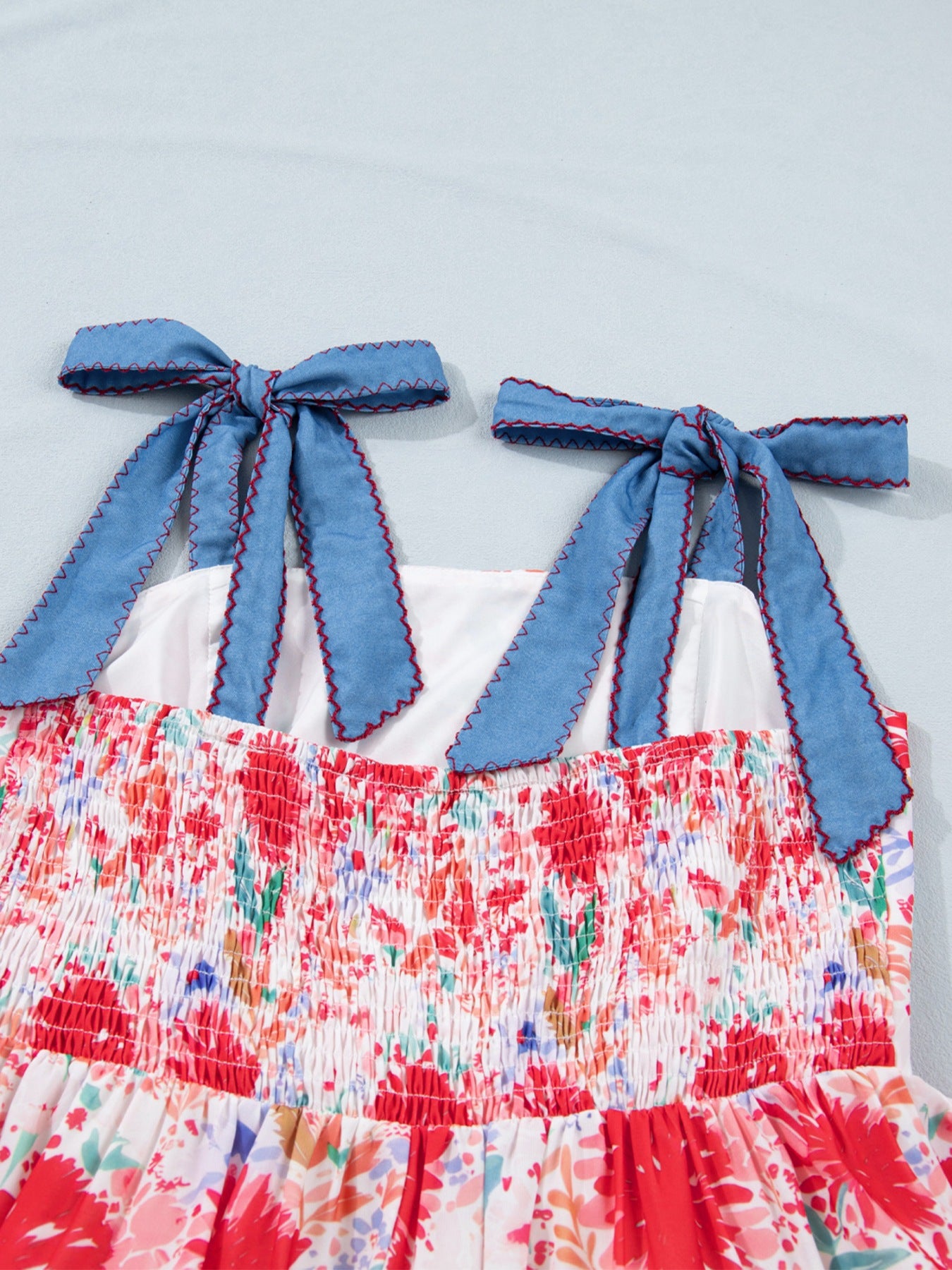 Floral print midi dress with smocked bodice and blue tie-shoulder straps.