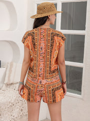 Bohemian print cap-sleeve playsuit in orange with detailed patterns, featuring a V-neck and short sleeves.