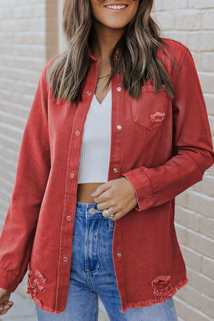 Rust distressed denim shirt jacket with raw edges and button front.