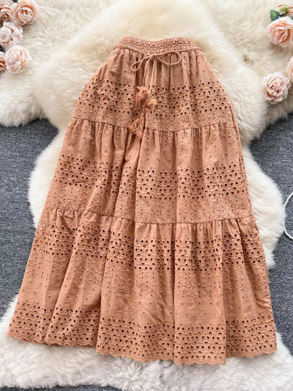 Light brown eyelet tiered maxi skirt with drawstring waist and tassel detail.