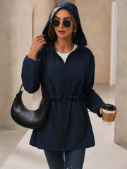 Navy hooded windbreaker jacket with ruffled drawstring waist and zippered front.