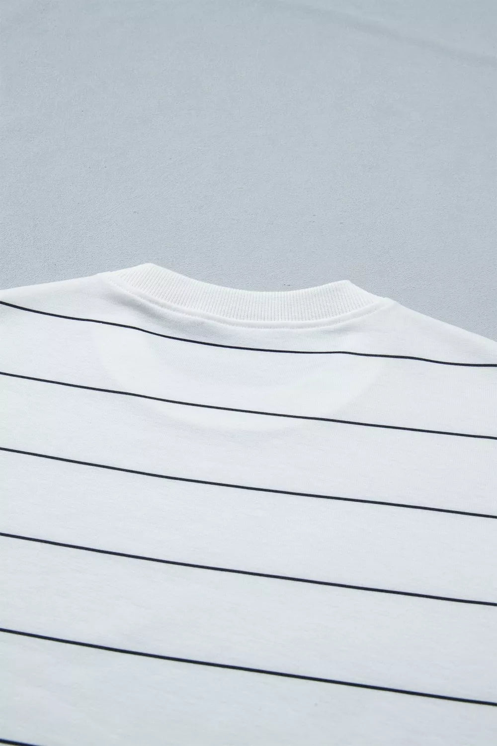 White polyester tee with black horizontal stripes and ribbed crew neck.