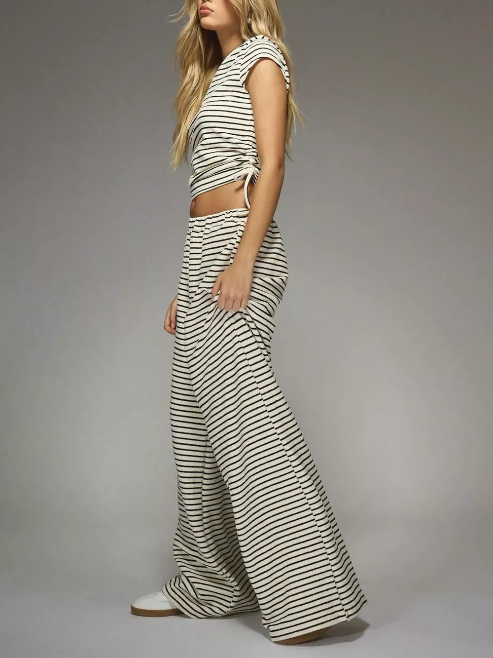 Off-white and black striped crop top with adjustable tie and wide-leg pants.