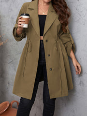 Olive green trench coat with gathered waistline, roll-tab sleeves, and button closure.