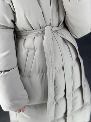 Ivory white padded trench coat with tie belt and pocket detail.