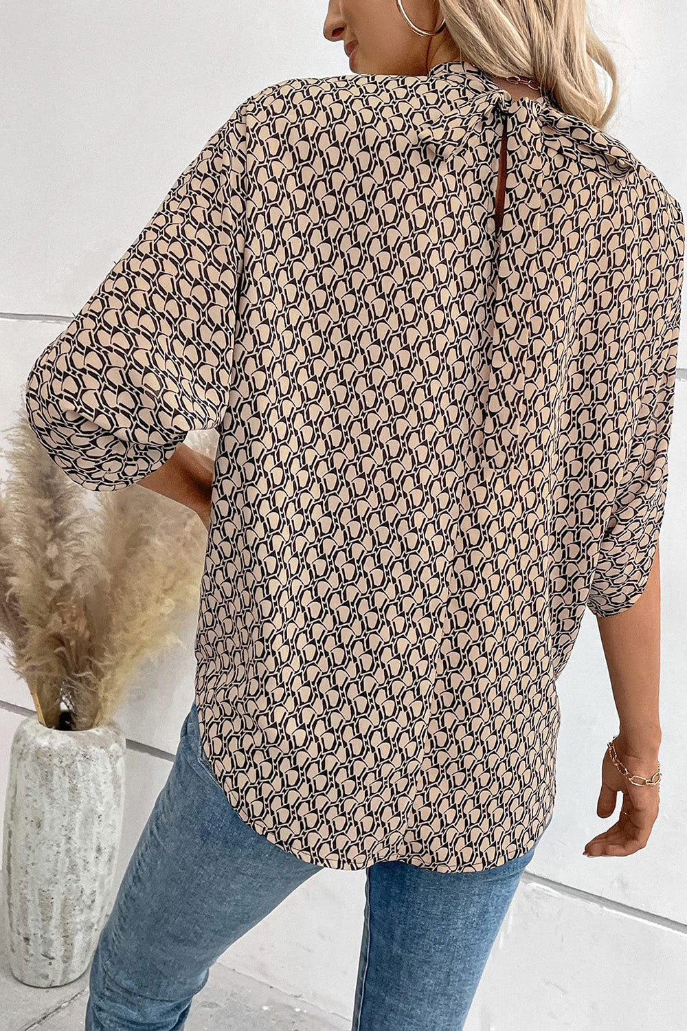 Blouse with geometric print, drape sleeves, and keyhole back tie detail.