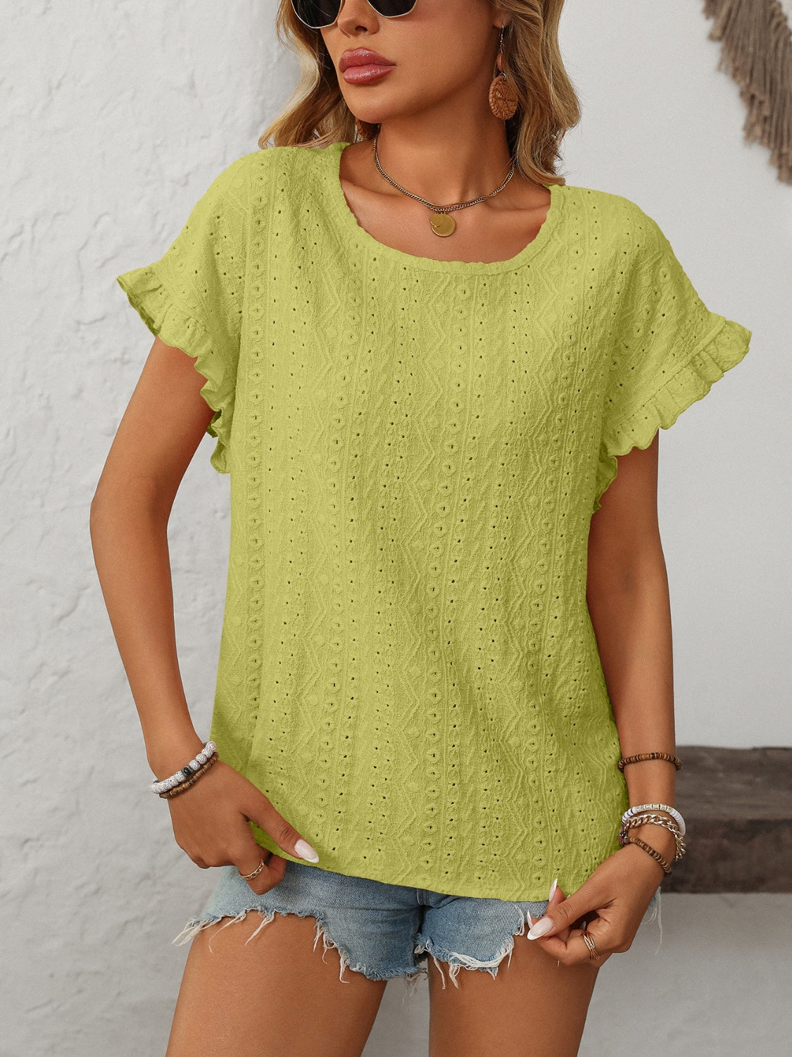 Yellow-green eyelet knit blouse with ruffled short sleeves and a scoop neckline.