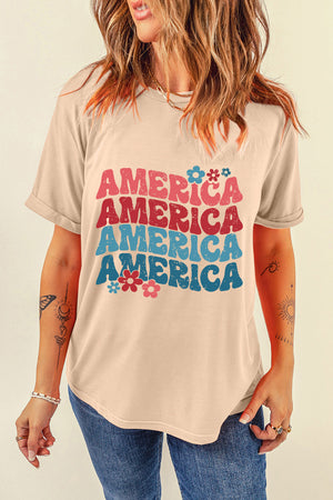 Tan t-shirt with stacked "America" graphic in retro font and floral accents.