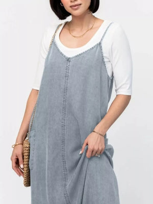 Light blue washed denim maxi dress with V-neck and adjustable straps, styled with a white tee.