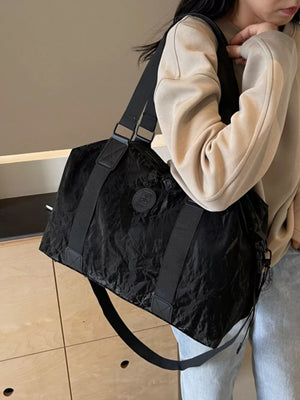 Chic black oxford cloth travel bag with adjustable strap and logo detail.