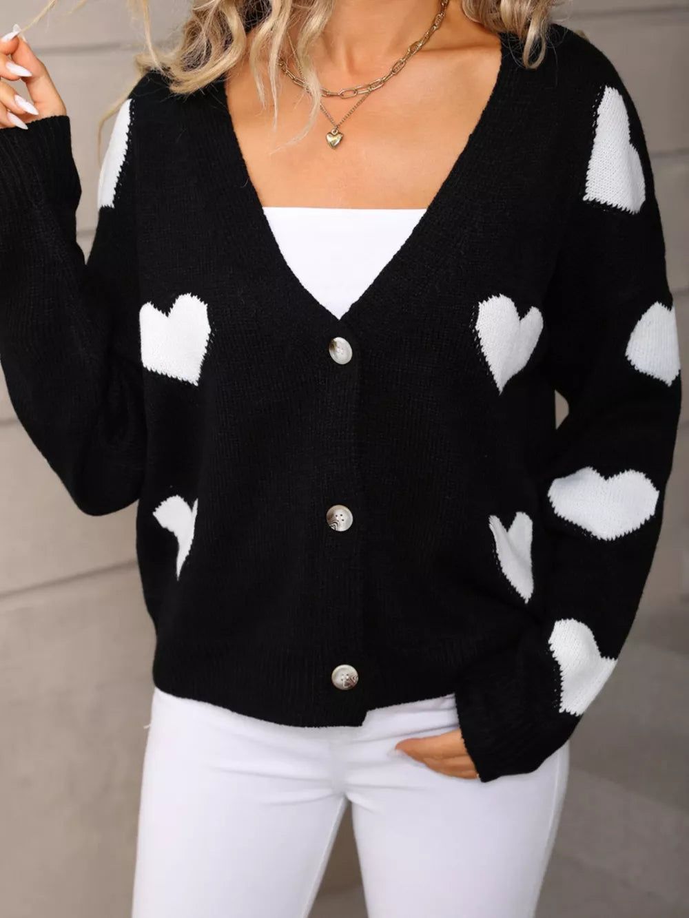 Black knit cardigan with white heart pattern, button-up front, V-neck.