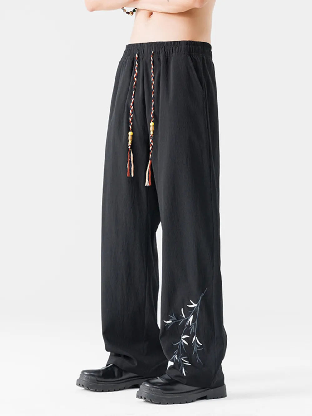 Black wide-leg men's sweatpants with embroidered bamboo detail and braided drawstring.